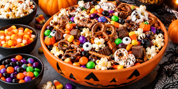Easy Halloween candy mix ideas for parties featuring colorful candy, popcorn, pretzels, chocolate treats, candy corn, and festive Halloween decorations