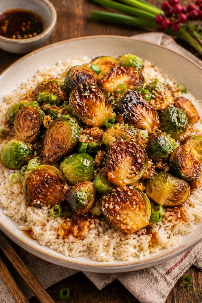Honey garlic roasted Brussels sprouts served over fluffy rice with sesame seeds and a glossy savory-sweet glaze in a modern winter dinner setting.