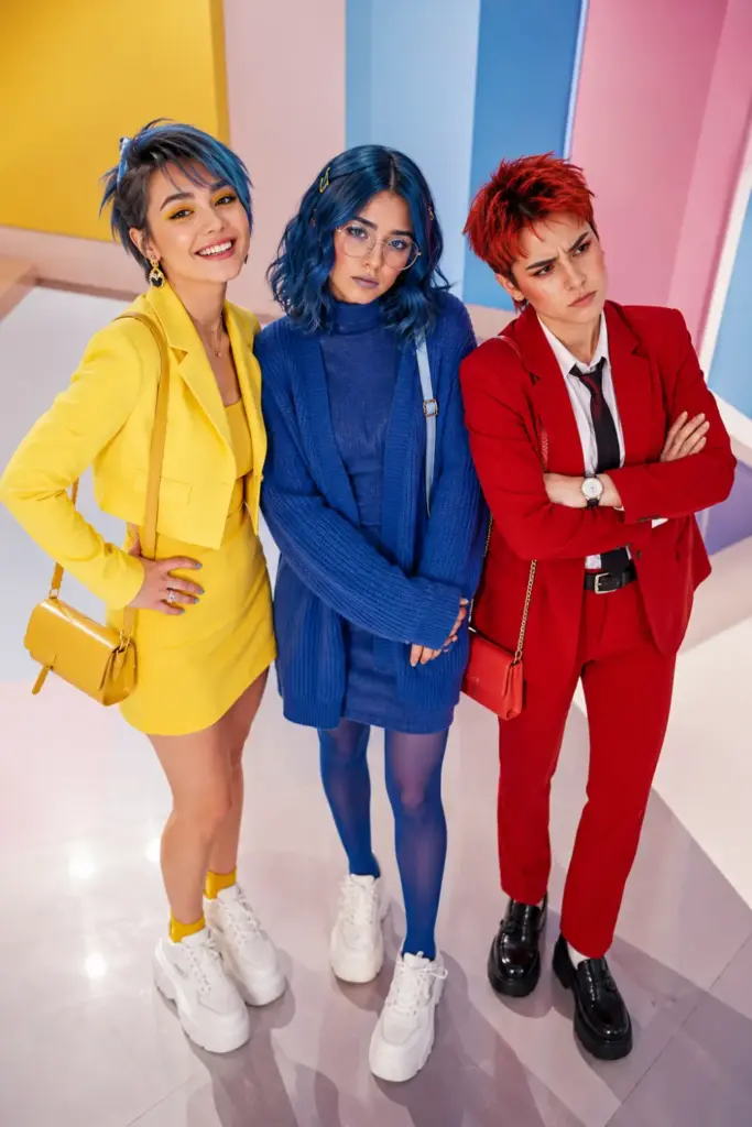 Three women wearing colorful modern Joy, Sadness, and Anger-inspired Halloween trio outfits with bright 2026 fashion, expressive makeup, coordinated accessories, and trendy shoes.