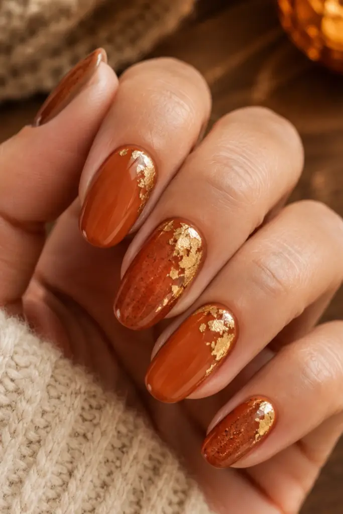 Rustic burnt-orange back-to-school nails with delicate gold foil accents for a chic fall-inspired manicure.