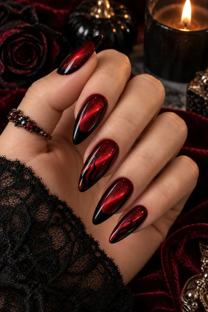 Deep blood red cat-eye Halloween nails with luminous magnetic shimmer and glossy black gothic details in a sophisticated 2026 manicure.