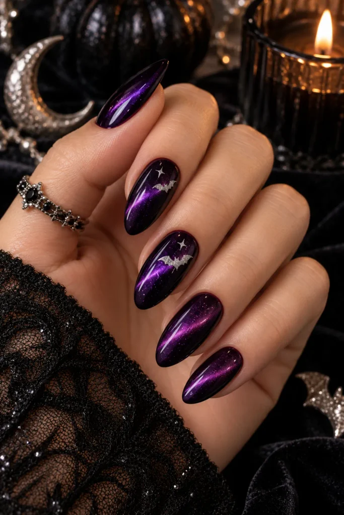 Midnight purple cat-eye Halloween nails with luminous magnetic shimmer and delicate silver bat accents, modern 2026 nail art.