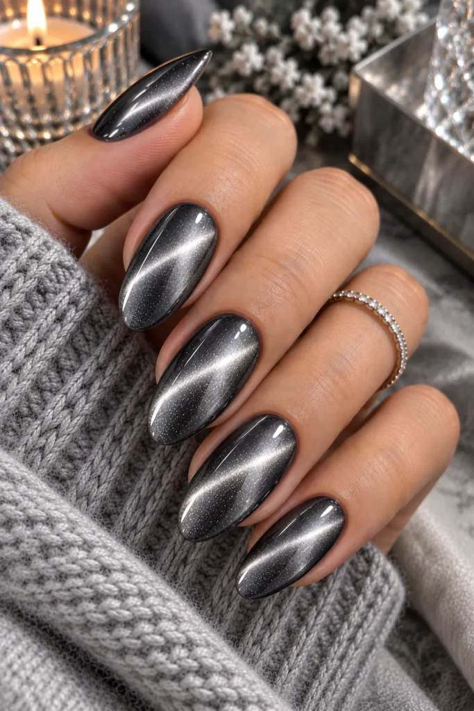 Smoky gray cat-eye winter nails with dimensional metallic shimmer, glossy almond shape, cool silver reflection, and contemporary luxe styling.